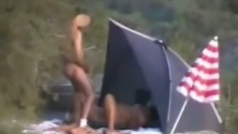 Two perverted guys pissing on a woman on a nudist beach